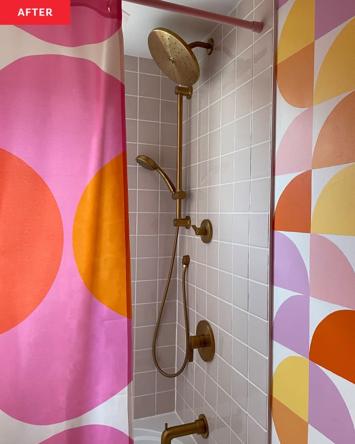 Bathroom after renovation:Shower with 60's pop style shower curtain with pinks, yellows, orange, light gray tile, bronze showerhead, wallpaper that matches shower curtain
