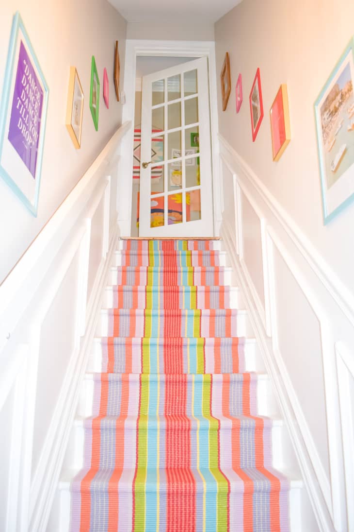 A staircase with a rainbow runner down the center of white stairs