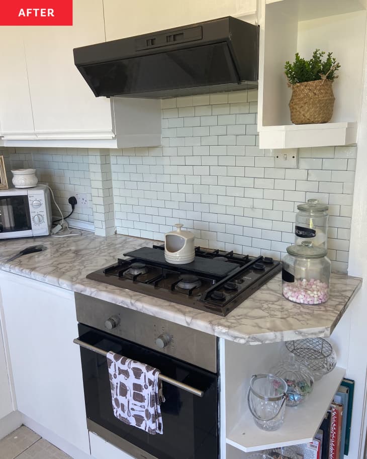 不wly renovated kitchen with grey marbled countertops, subway tiles and white cabinets.