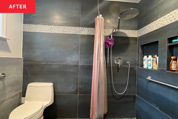Waterfall shower head in newly renovated shower with dark tiles.