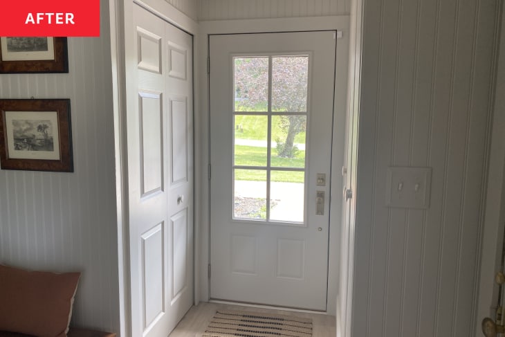 white door, glass panel window in door, white tongue and groove paneling, beige and black runner, burnt orange throw pillow, closet door, wood picture frames