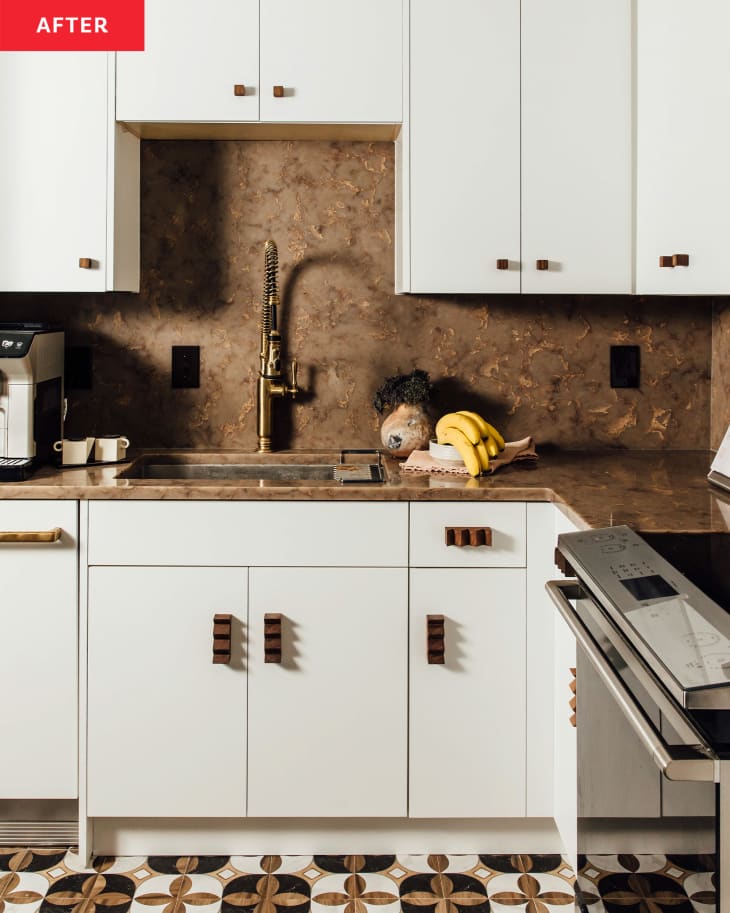 A renovated kitchen with dark countertops, white cabinets and tiled floors.