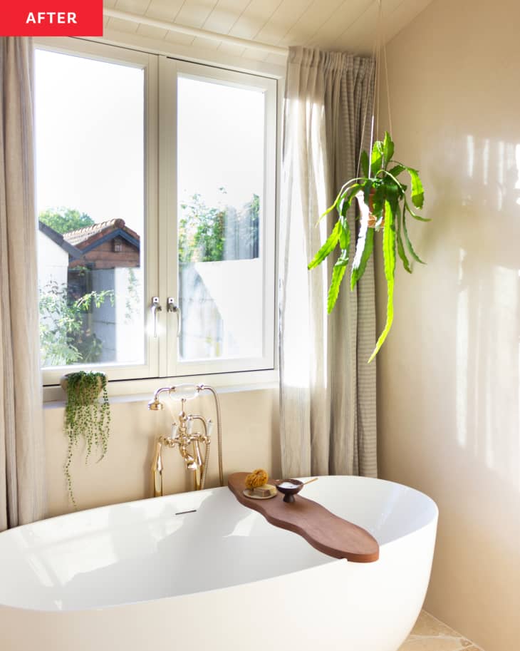 A large window above a tube in a beige bathroom