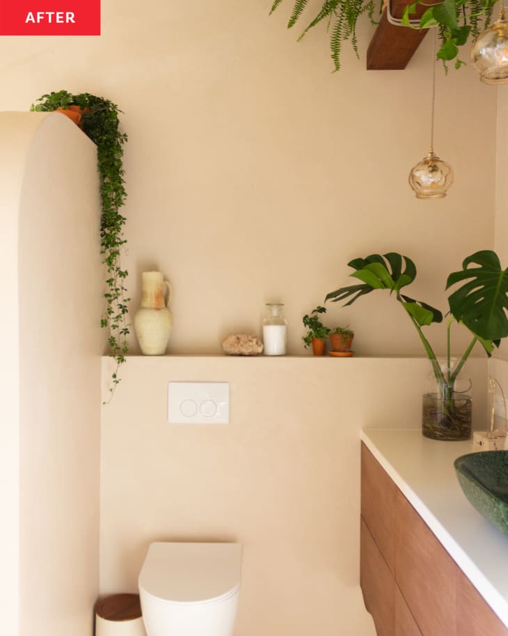 A toilet surrounded by plants  in a beige bathroom