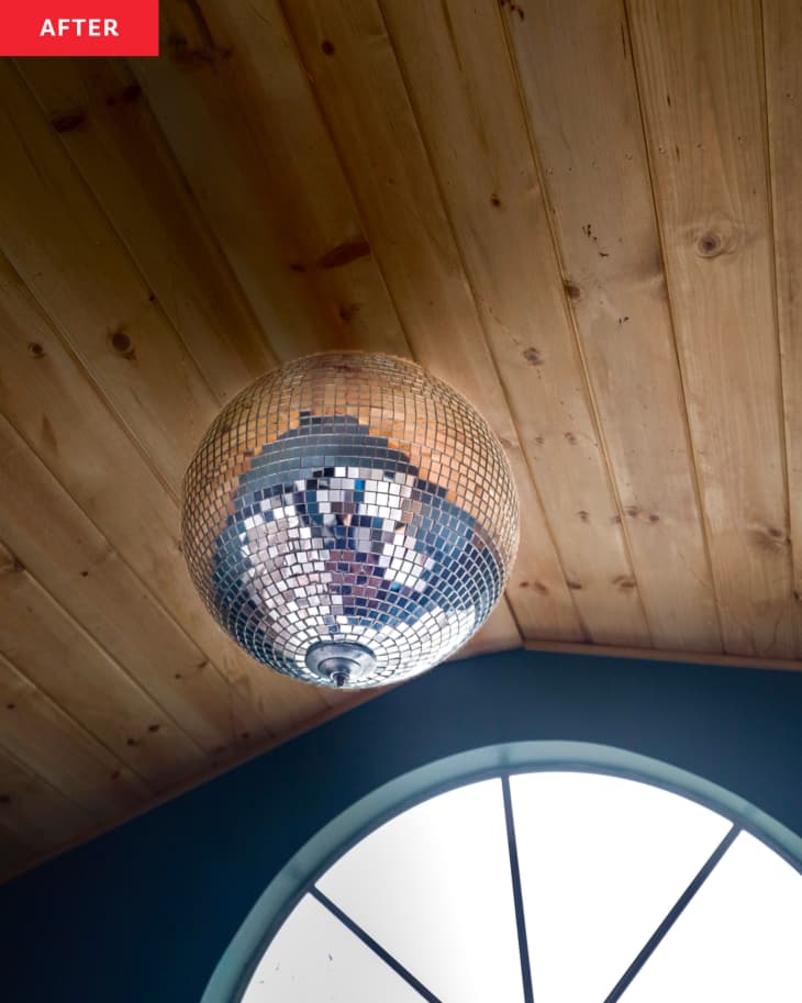 Disco ball hung on wood paneled ceiling.