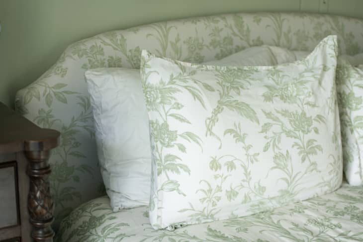 Close-up view of green-and-white floral print headboard with matching duvet cover.