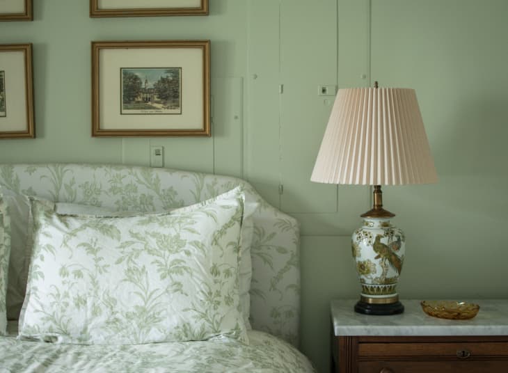 Bedroom with soft green walls and a green-and-white floral print headboard with matching duvet cover.