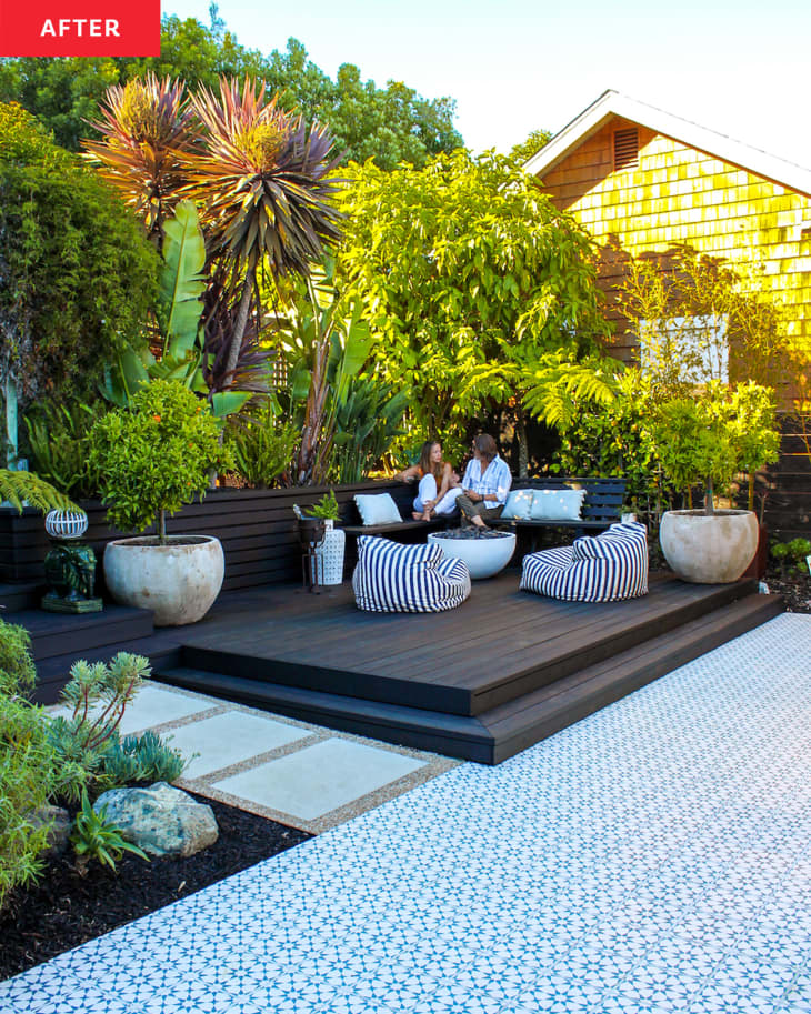 house with black and white tiled deck with wood accents in yard: fire pit