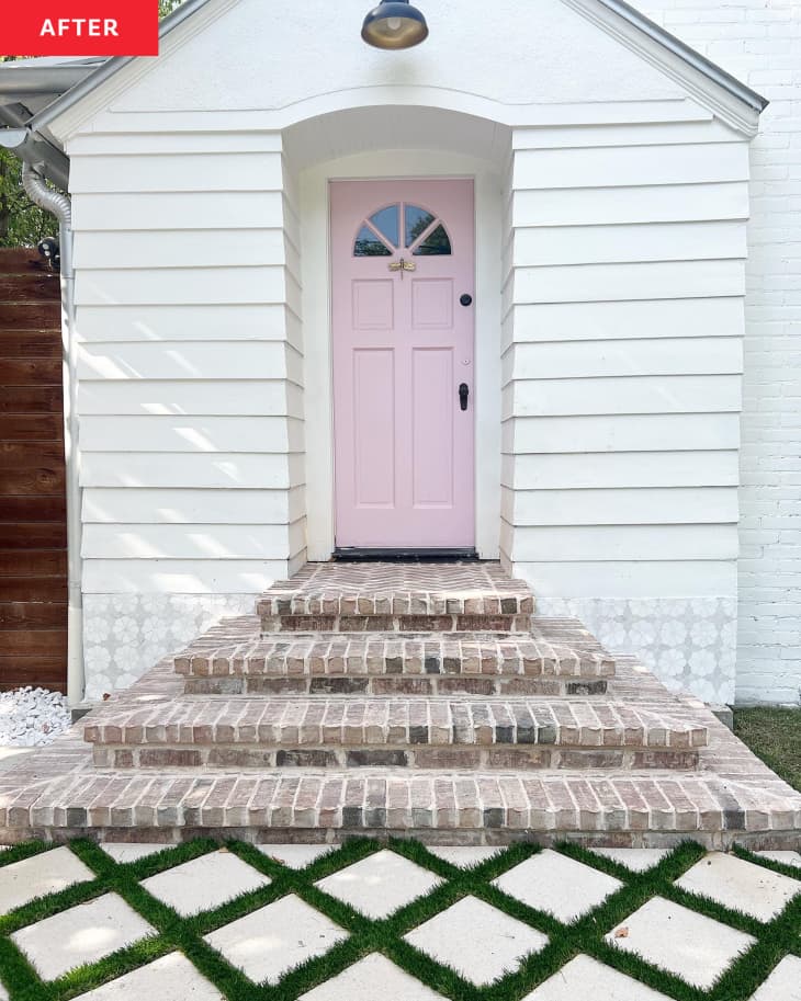 A white house with a pink front door and brick stairs