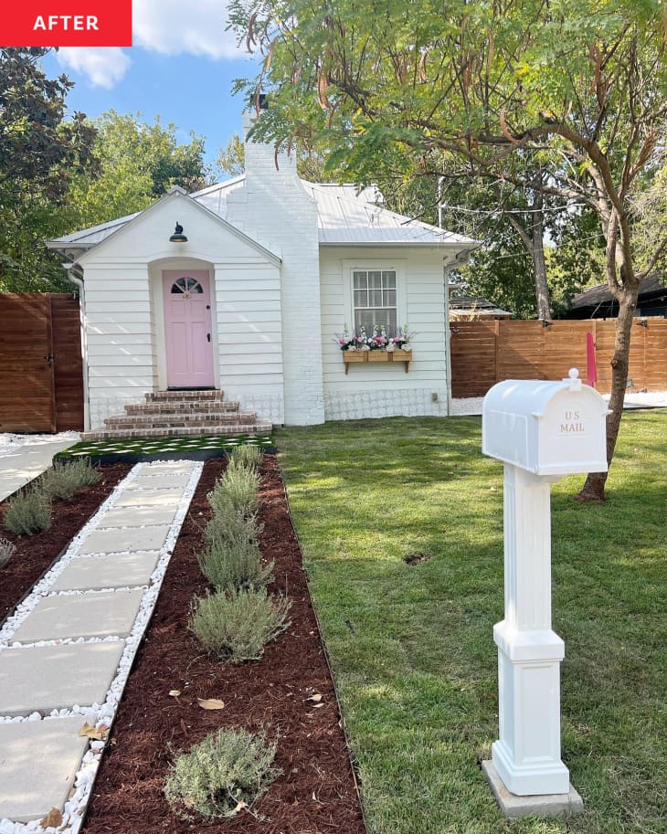 A small white house with a pink front door and a white mailbox