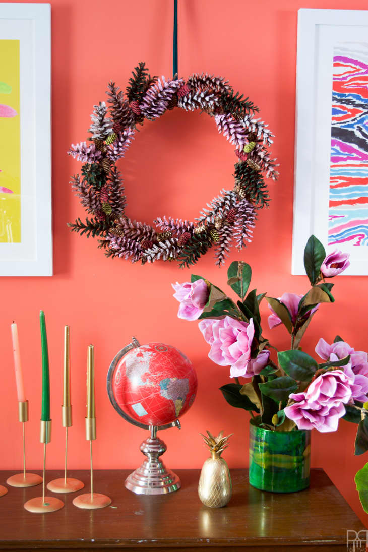 Round wreath made with pinecones that are painted in red, green, white, and pink