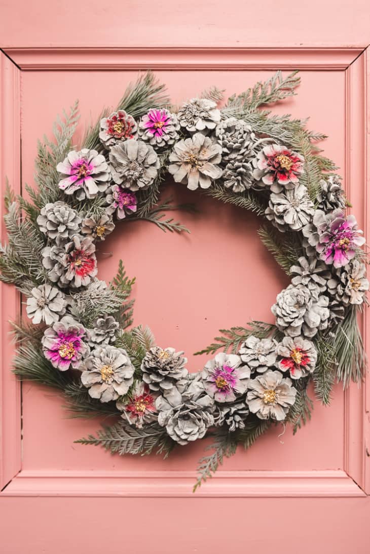 Evergreen wreath embellished with pinecones painted to look like flowers