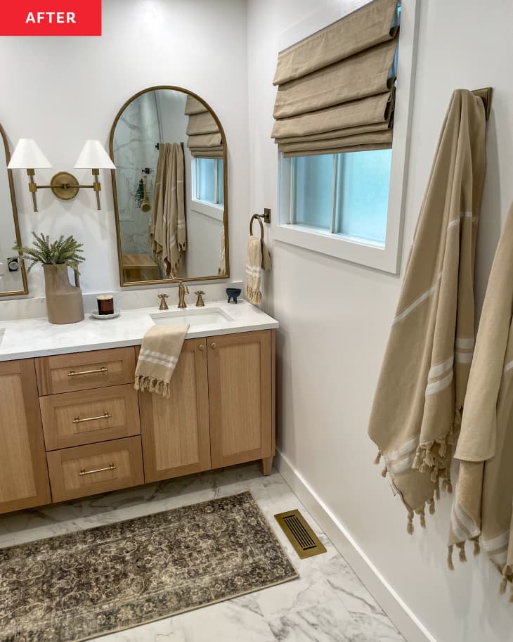 Bathroom whitestone countertop with wooden cabinets, and large framed mirrors.