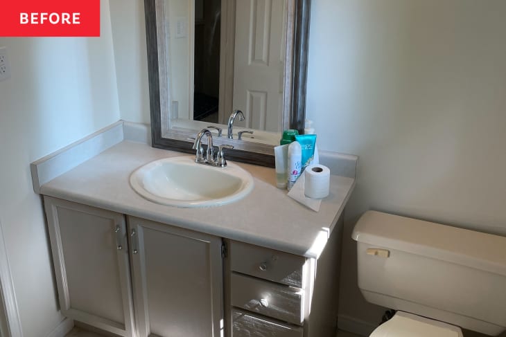 A bathroom counter with white sink and grey cabinets