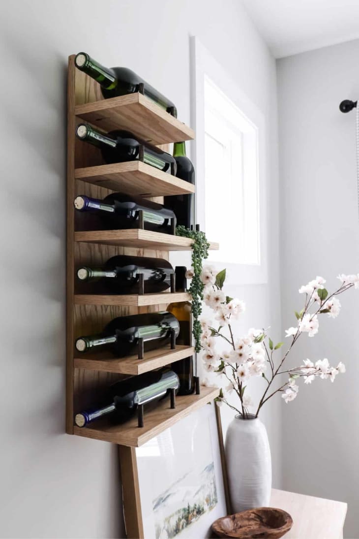 Minimalist wall-mount wood wine rack with storage for six horizontal bottles and two vertical bottles.