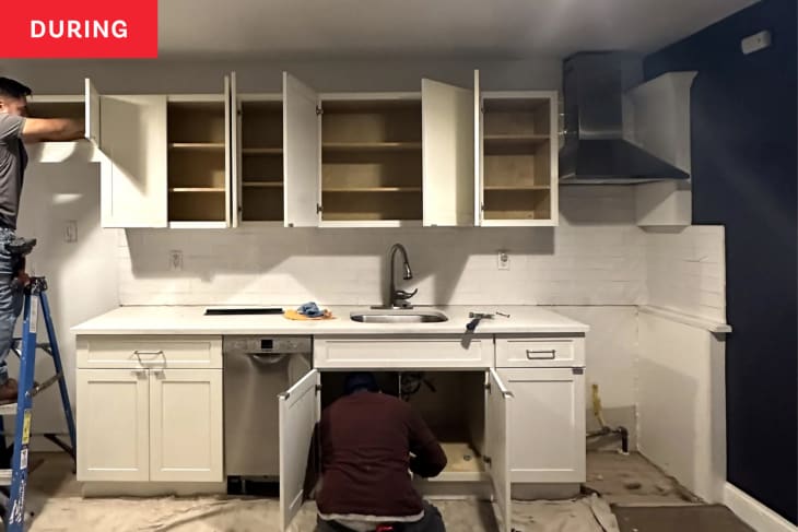 A kitchen with white cabinets is in the process of renovation.