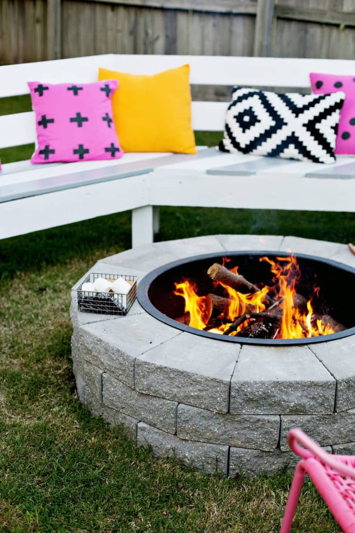 Stone fire pit surrounded by white painted wood benches