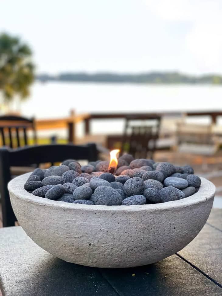 DIY tabletop fire pit made using a concrete bowl filled with stones and a wick for the flame.