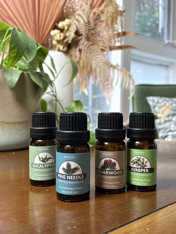 Bottles of essential oils on a table, including eucalyptus, pine needle, cedar wood, and juniper.