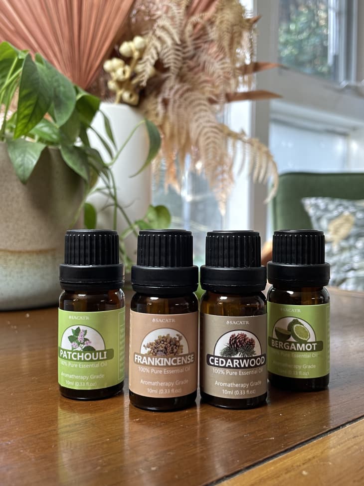 Bottles of essential oils on a table, including patchouli, frankincense, cedar wood, and bergamot.