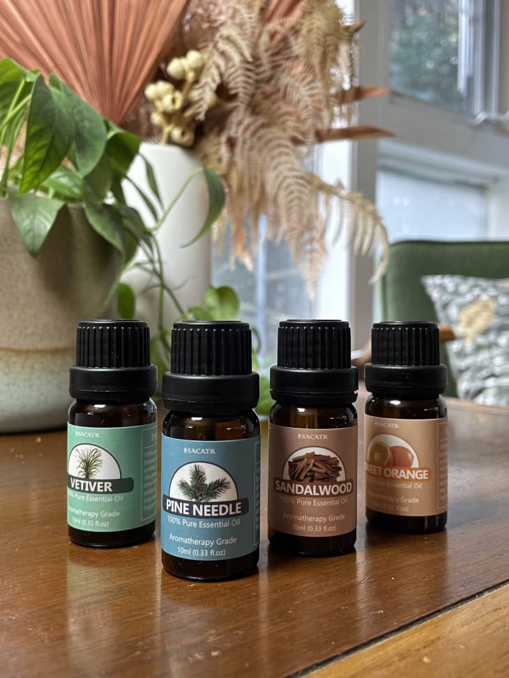 Bottles of essential oils on a table, including vetiver, pine needle, sandalwood, and sweet orange.