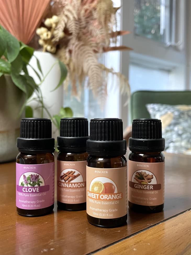 Bottles of essential oils on a table, including clove, cinnamon, sweet orange, and ginger.