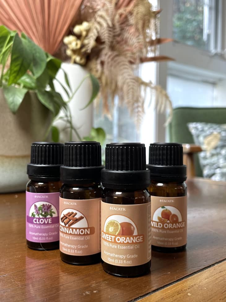 Bottles of essential oils on a table, including clove, cinnamon, sweet orange, and wild orange.