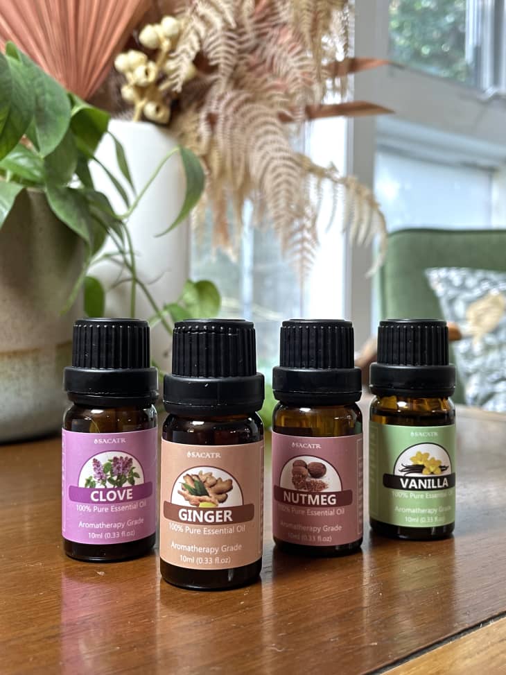 Bottles of essential oils on a table, including clove, ginger, nutmeg, and vanilla.
