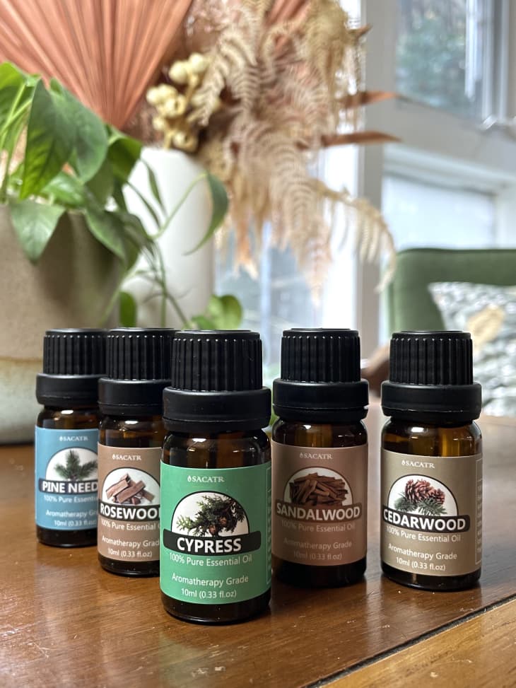 Bottles of essential oils on a table, including pine needle, rosewood, cypress, sandalwood, and cedar wood.