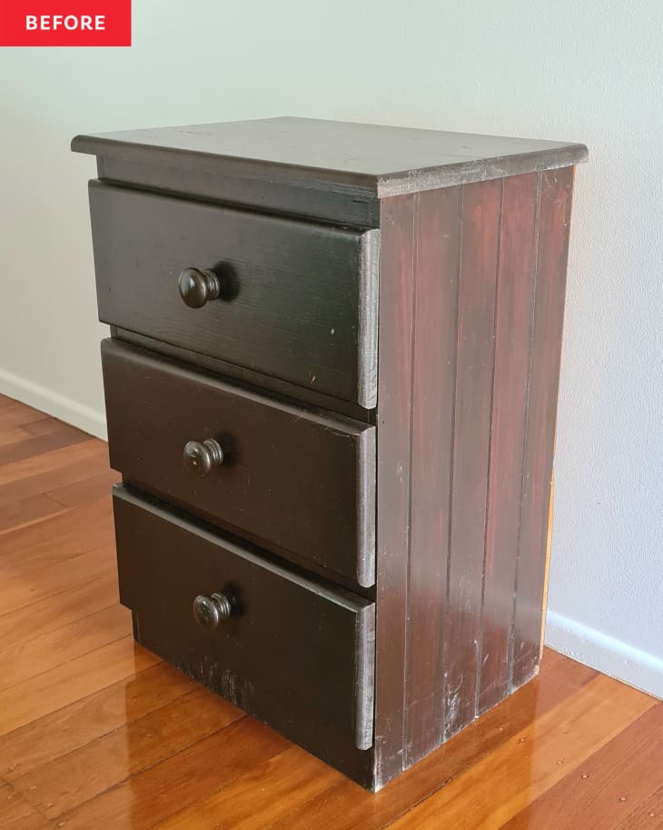 A brown three drawer night stand in a bedroom.