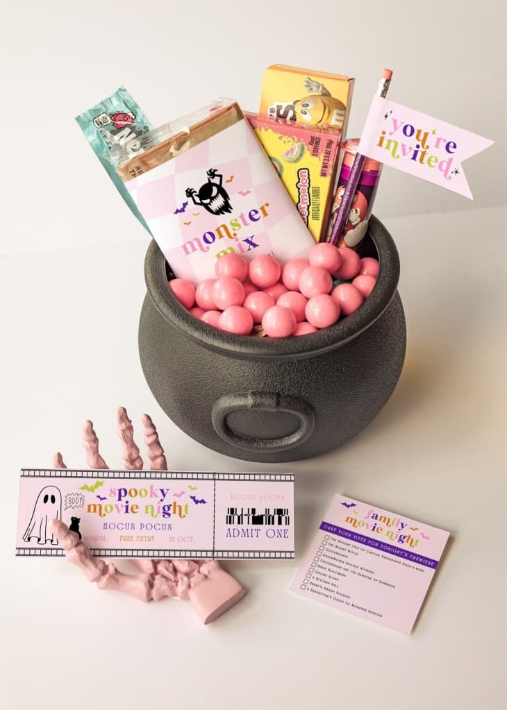 Plastic cauldron with candy and other treats inside, including a printed ticket to a movie night.