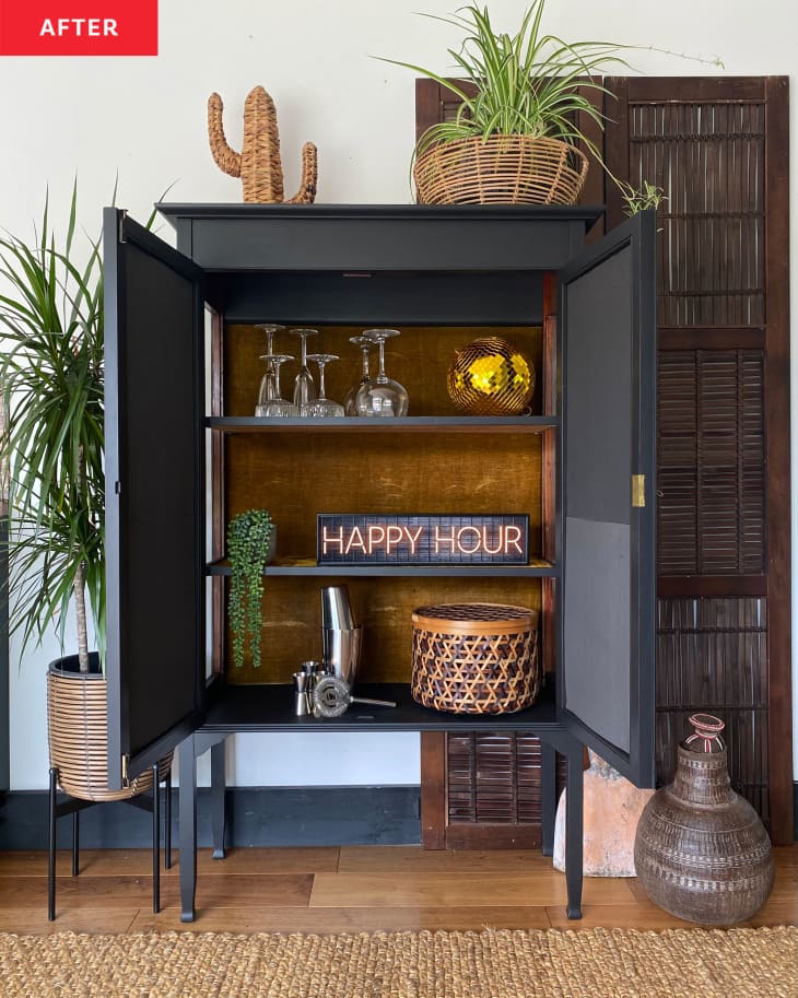 An open black cabinet with glasses and decor
