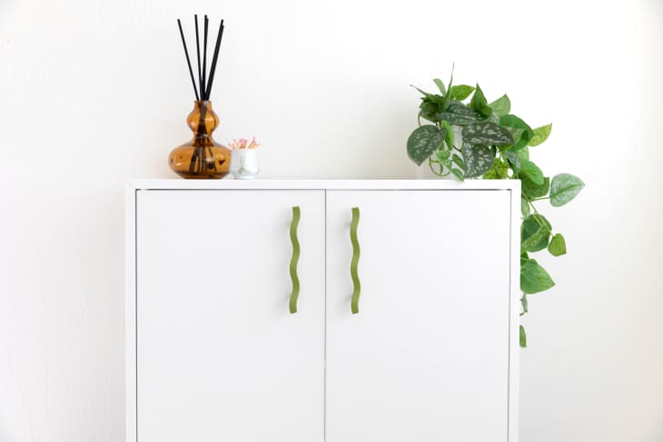 White cabinet with wavy green pulls on both doors