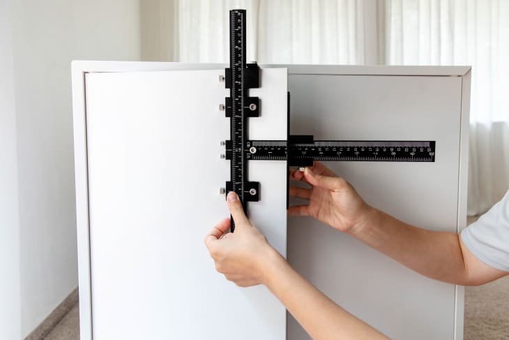 Using a cabinet hardware jig to measure where to place hardware holes on a cabinet door