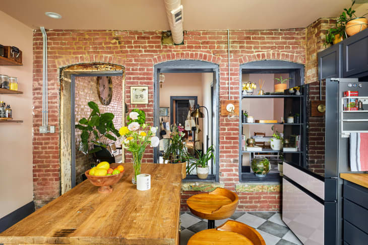 peach kitchen with large wood center island, exposed brick wall, and rustic details after renovation