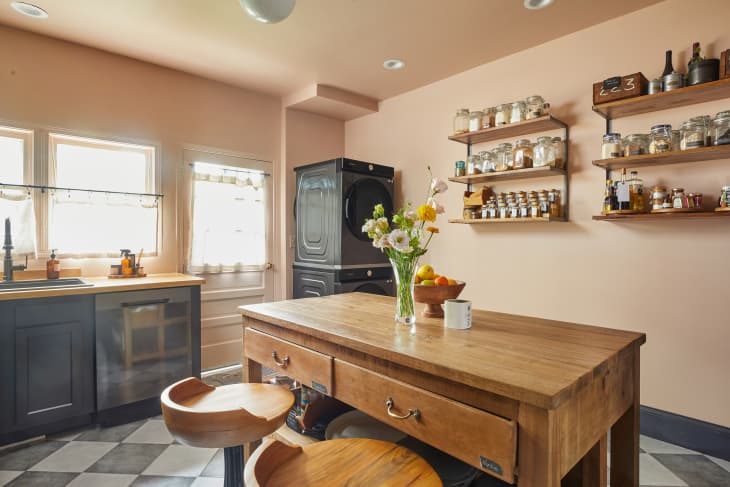 warm peach kitchen with large wood center island, gray cabinets, distressed checked floor after renovation