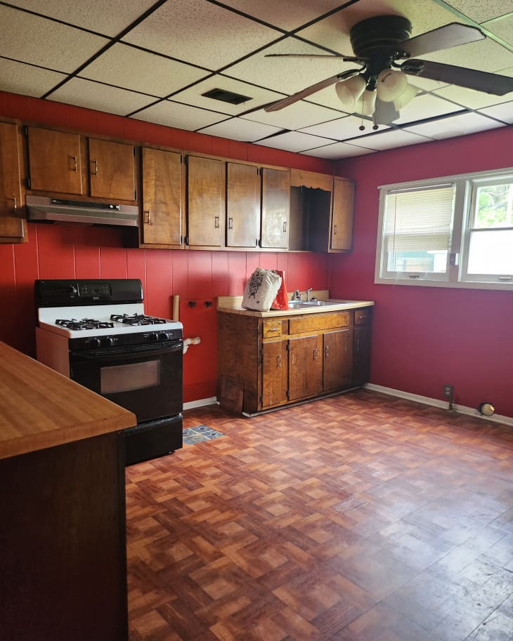 kitchen with red walls, wood cabinets, and reddish parquet flooring before renovation