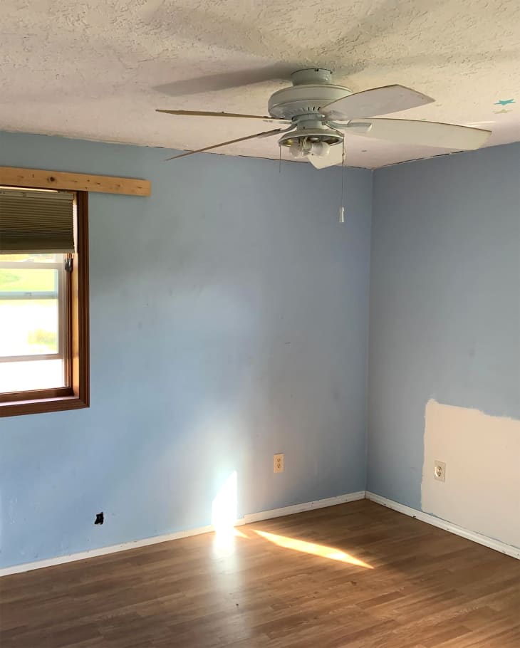 Ceiling fan in blue painted bedroom before renovation.