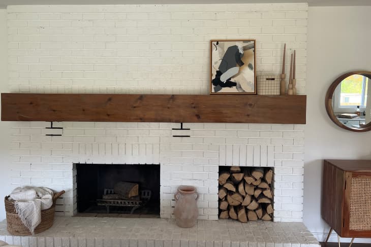 Abstract painting set on top of wooden mantel on white painted fireplace.