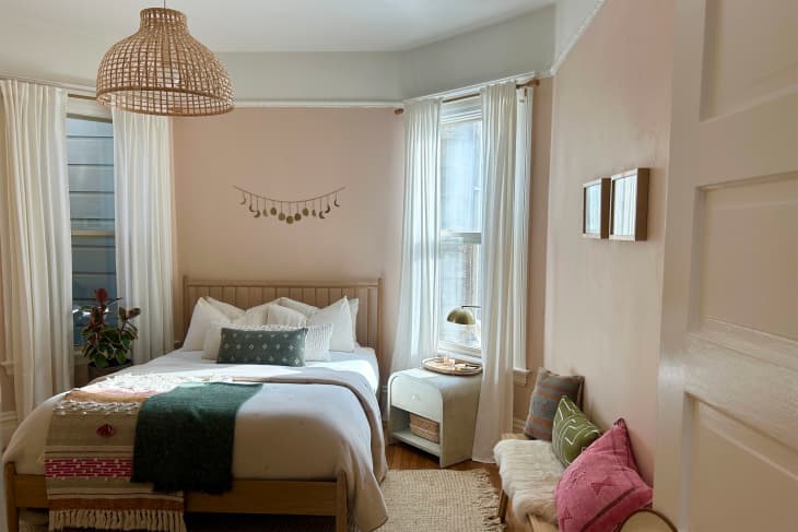 Straw woven pendent hanging in pink painted bedroom.