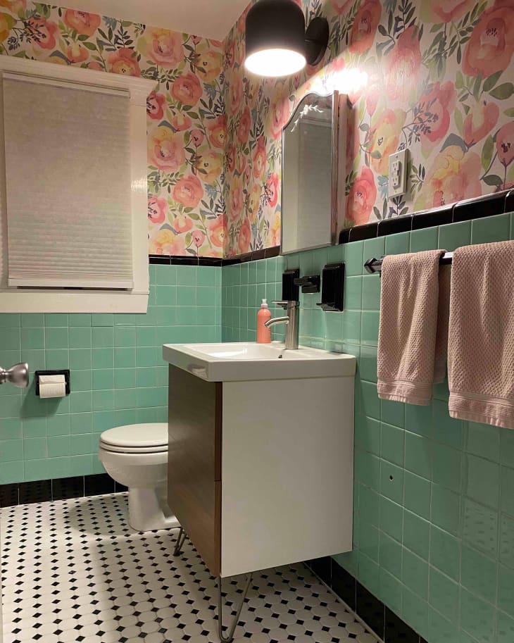 Green tiles in bathroom with newly installed floral wallpaper.