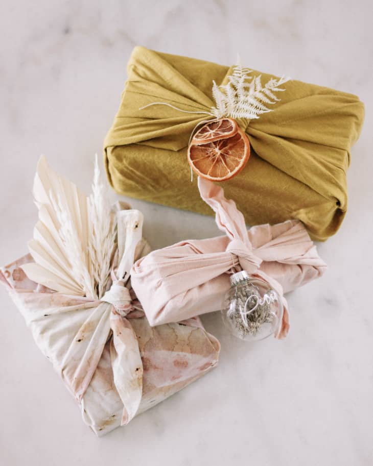 Gifts wrapped in fabric and decorated with dried leaves and fruits.