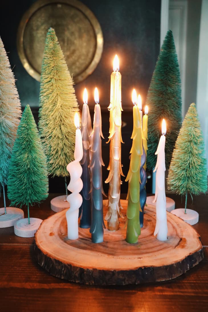 Candelabra made with a rough-hewn slice of log fitted with taper candles in shades of green and white.