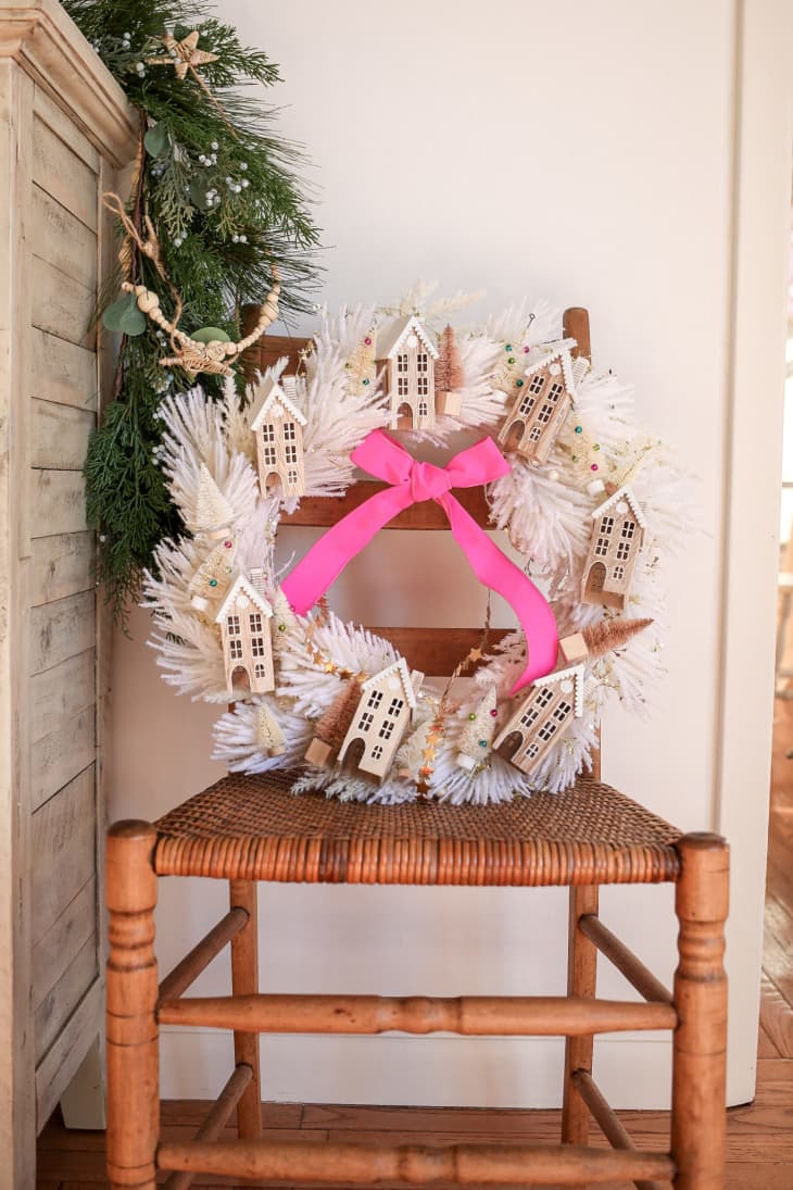 Wreath made with pampas grass and decorated with miniature houses and Christmas trees in shades of brown and tan.