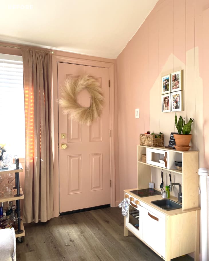 Door with wreath and IKEA play kitchen in living room with pink walls