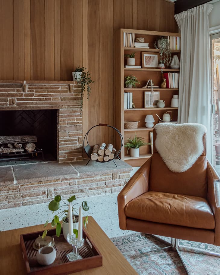 Leather armchair in living room with wood paneled fireplace.