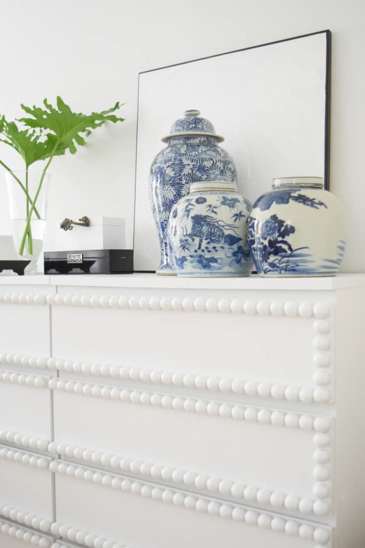 white dresser with round button details on drawers and blue and white ceramic vases
