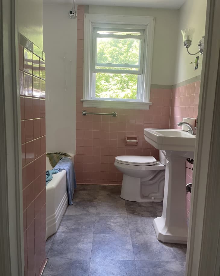 white bathroom with pink tile and gray floor before remodel