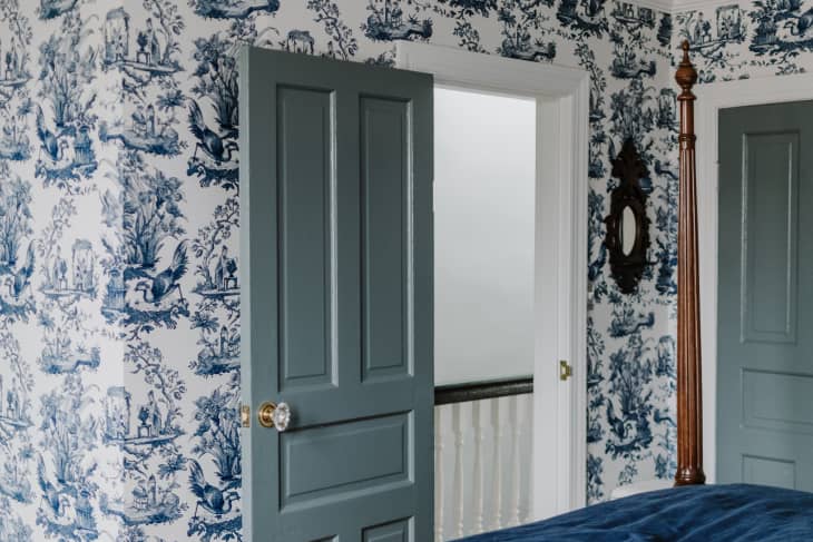Sea foam blue painted door with crystal door knob, blue toile wallpaper, open door to upstairs hallway