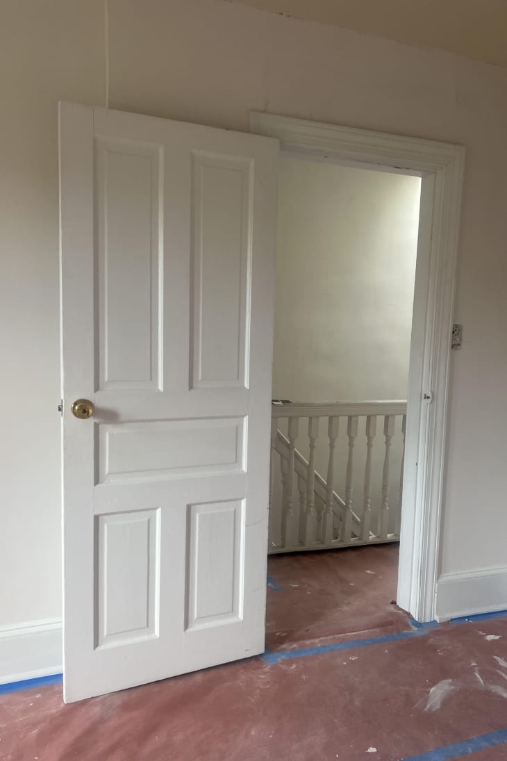 White door with view to upstairs hallway with painting paper on floor